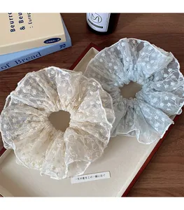 Detailed macro view of two floral lace scrunchies in cream white and light blue colors