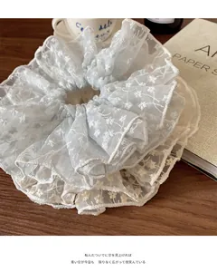 Detail of light blue organza scrunchie with white floral embroidery on a wooden surface