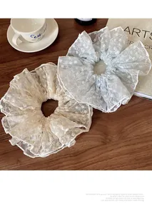 Detail of vintage French lace scrunchies with floral embroidery on light blue and cream gauze