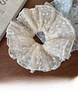 Detailed macro view of lace scrunchies with floral embroidery on a rustic wooden desk