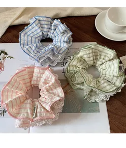 Detailed view of mint green, blue and pink plaid hair scrunchies with white lace trim