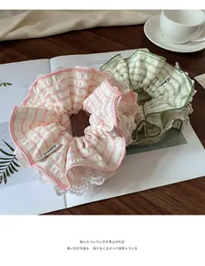 Detail of mint green and pink seersucker scrunchies with white lace and brand label