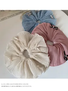 Detailed macro view of soft pleated scrunchies with pearls and mini bows in three colors