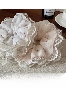 Detalle de coleteros florales con ribete de encaje blanco sobre un fondo beige suave