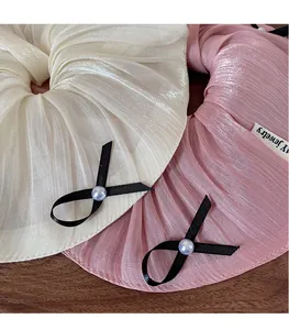 Detail of pink scrunchie with satin sheen, black ribbon bow and elegant white pearl