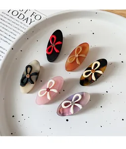 Detailed macro view of 6-piece acetate hair clips with bow designs and shiny rhinestones