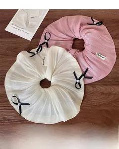 Detail of pink and cream satin scrunchies with bows, pearls, and brand tag labels