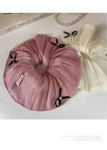 Detailed view of silk hair scrunchies with pleated texture, black bows, and pearl accents