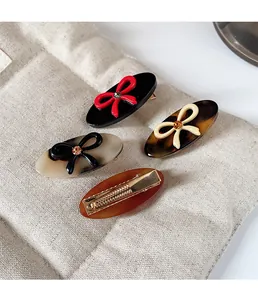 Detailed view of four acetate bow hair clips with rhinestones and metal duckbill clips