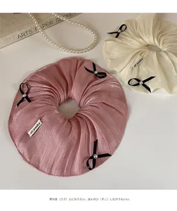 Detail of pink and cream satin scrunchies with black bows and pearl accents