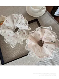 Detalle de coleteros florales con encaje blanco en una bandeja con taza de café