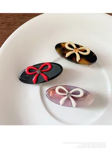 Three-piece set of oval hair clips featuring colorful resin bows and sparkling rhinestones