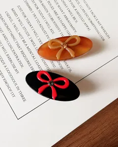 Detailed view of vintage acetate hair clips with crystal bows on a decorative card