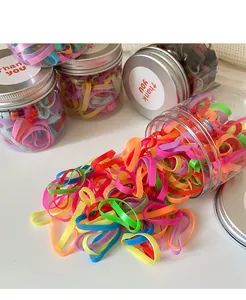 Close-up of colorful elastic hair bands spilling from a jar for kids hair styling