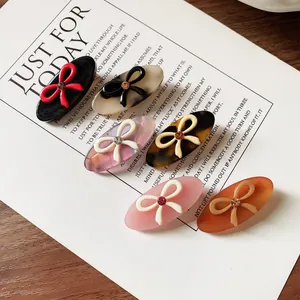 Set of 6 vintage acetate hair clips with crystal bow designs on wood background