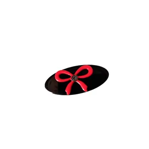 Elegant oval hair clip with red bow and sparkling crystal accent on black base