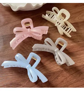 Set of four pastel bow hair claws in pink, beige, blue and silver on wood background