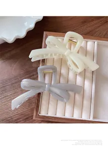 Detailed view of large cream and grey bow hair claws in an elegant jewelry tray