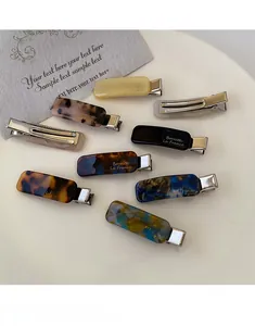 Detailed close-up of colorful acetate rectangle duckbill hair clips on white plate