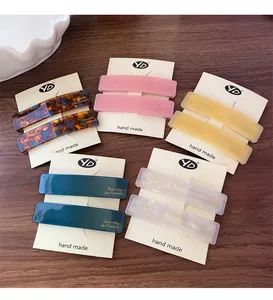 Detail of five assorted colorful acetate hair clips on display cards on wooden table