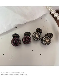 Detailed view of four mini resin hair claws with glittering rhinestones on a ceramic tray