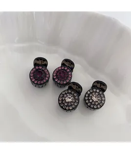 Detail showing four mini claw clips with sparkling rhinestones in a white ceramic bowl
