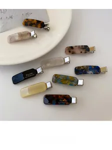 Detailed close-up of acetate hair clips with gold lettering and marble patterns