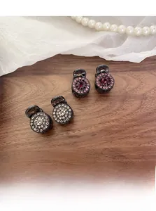 Close-up of four mini round rhinestone hair clips set on elegant dark wood surface