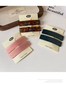 Detail view of acetate resin barrette hair clips on a card featuring marbled and matte textures
