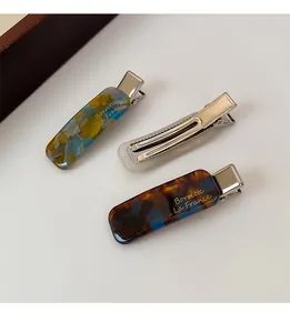 Detail of tortoise shell acetate hair clips with golden lettering and metal grip