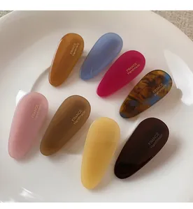 Détail de barrettes à cheveux colorées en acétate présentées dans un bol en céramique