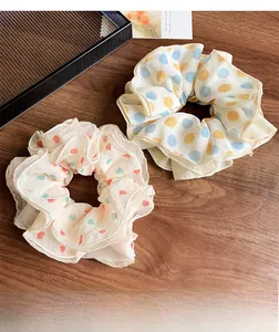 Detail of two chiffon scrunchies with heart and polka dot prints on a wooden surface