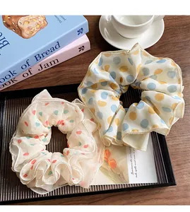 Close-up of chiffon scrunchies with polka dots and floral patterns on a striped tray