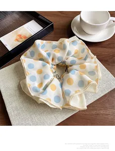 Detailed view of cream fabric scrunchie with colorful polka dots on a wooden table