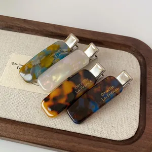 Elegant 4-piece acetate hair clip set with marble patterns and gold lettering on a tray