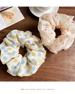 Detail of two chiffon scrunchies with polka dot and heart patterns on a wooden table