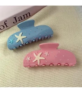 Macro detail of two starfish hair claws in blue and pink with sparkling rhinestones