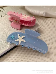 Close-up of pink and blue starfish hair claws with matte texture and sparkling rhinestones