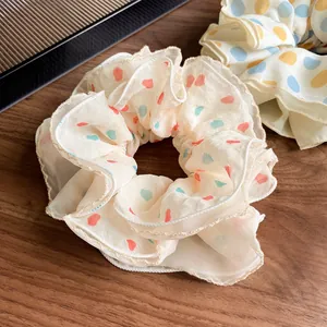 Sheer heart-patterned oversized hair scrunchie with red and green polka dots on cream fabric