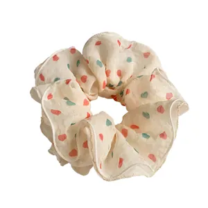 Cream scrunchie with colorful heart pattern and soft pleated texture for hair