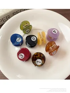 Dettaglio di otto mini fermagli per capelli stile biliardo in un piatto di ceramica