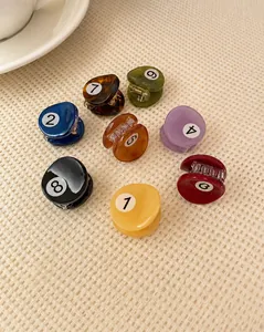 Détail de pinces à cheveux boules de billard colorées en acétate sur fond tissé