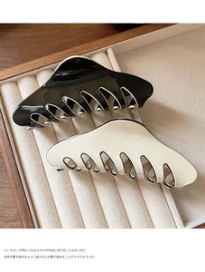 Detailed view of large black and beige matte hair claws on a soft jewelry tray