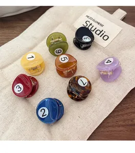 Dettaglio di mini mollette colorate da biliardo numerate da uno a nove su tessuto beige