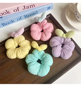 Close-up of four floral hair scrunchies in pastel colors on a wooden tray with books