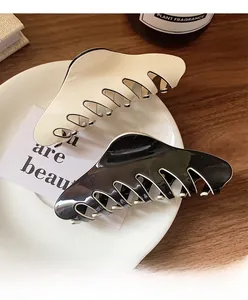 Detail of cream white and glossy black French hair claws set on a ceramic tray