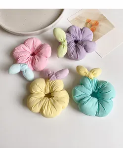 Close-up of four colorful floral scrunchies with 3D petals and soft fabric details