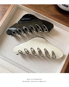 Close-up of minimalist black and beige hair claw clips with contrast edge on a wooden tray