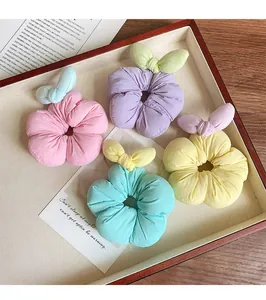 Detail of four pastel flower scrunchies with bunny ears in a wooden tray
