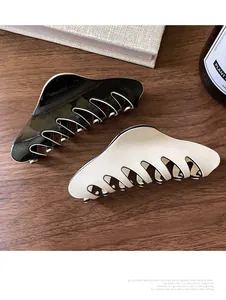 Close-up of high-gloss black and white French hair claws on a textured wooden background